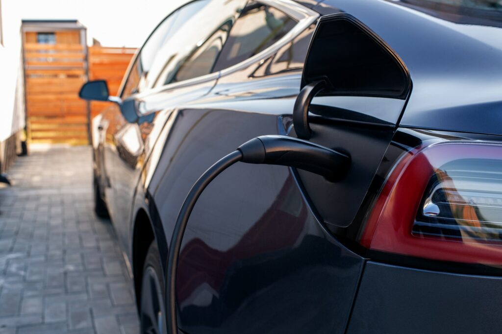 Back of black car with plugged charger during fueling process
