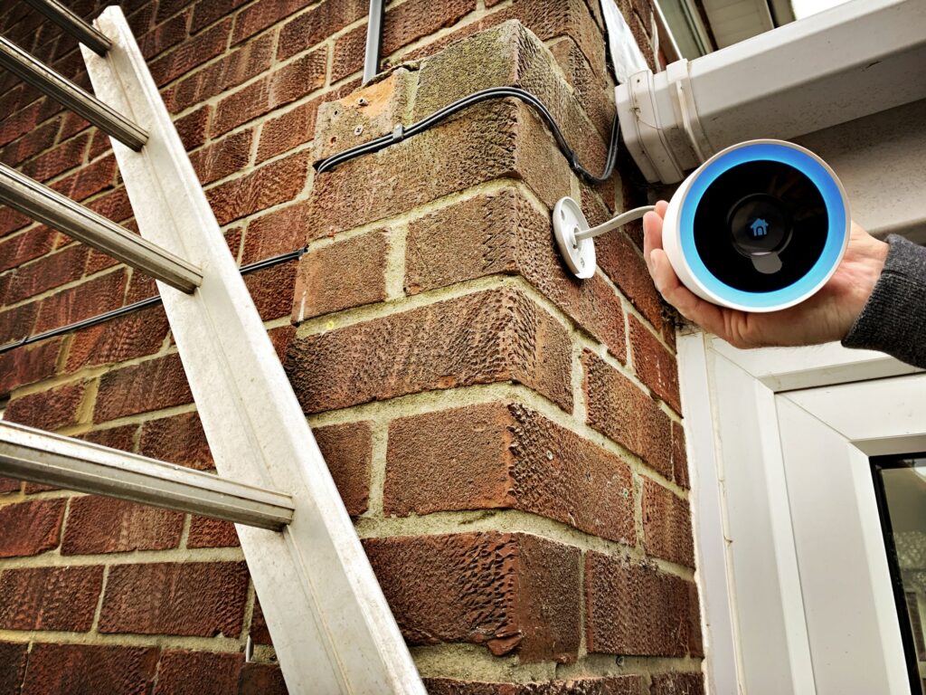Close up view of a homeowner installing a Google Nest CCTV home security camera over the front door